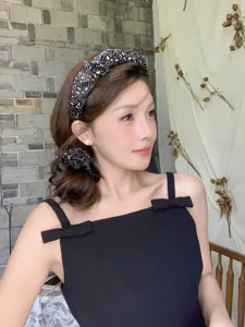 Modelo asiática con diadema de diamantes de imitación negros y coletero de satén a juego
