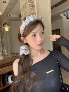Modelo con diadema de satén plisado plateado y coletero de strass a juego en café
