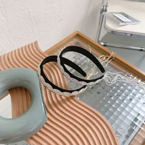 Schweres Strass-Stirnband mit langen Quasten auf gewelltem Holzbrett, Retro-Stil