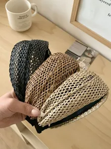 Gros plan de trois serre-têtes en paille tressée à la main en noir, marron et beige