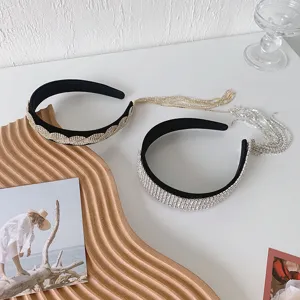 Detailansicht von zwei eleganten Strass-Stirnbändern mit Quasten auf Holztablett