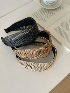 Gros plan de trois serre-têtes en paille tressée de couleur noire, brune et beige