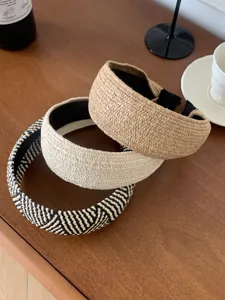 Détail de trois serre-têtes en paille tressée à la main, naturels et à chevrons.