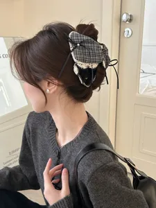 Detailansicht einer stilvollen Haarklammer mit karierter Schleife und Spitzenbändern am Haar.