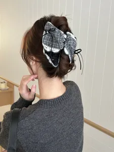 Detailaufnahme einer eleganten schwarz-weiß karierten Schleifen-Haarklammer am Model