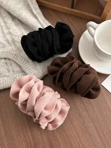 Detail view of soft pleated fabric banana hair clips in pink, brown, and black colors