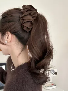Side view detail of a stylish dark brown fabric flower banana clip on a woman's ponytail