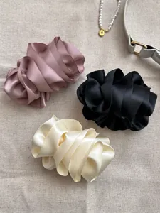 Detail view of premium satin pleated bubble flower hair clips in pink, black, and cream