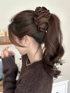 Detail showing a Korean style brown fabric flower banana hair clip in a ponytail.