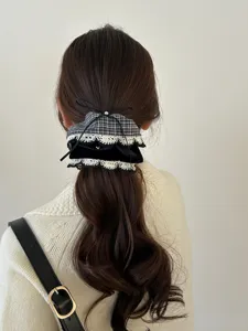 Detailansicht einer karierten Haarschleife mit weißer Spitze und schwarzem Band