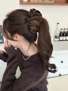 Macro view of a large brown ruffled fabric flower banana clip for elegant winter hairstyles