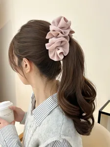 Close-up detail of a stylish pink ruffled fabric banana clip worn on a ponytail