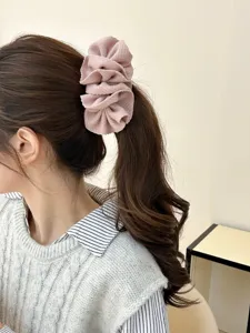 Detailed view of an elegant pink ruffle fabric banana hair clip worn on a high ponytail