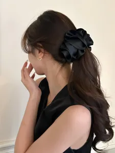 Detailed close-up showing a black satin ruffled flower banana hair clip on a ponytail