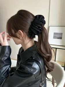 Elegant large black ruffled fabric banana clip hair accessory worn on a ponytail