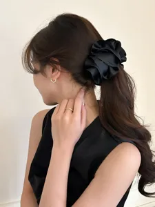 Close-up of elegant black satin pleated flower banana clip on a woman's ponytail
