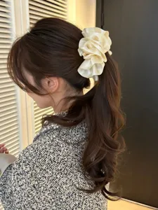 Detailed close-up view of a cream satin pleated flower banana clip on a ponytail hairstyle