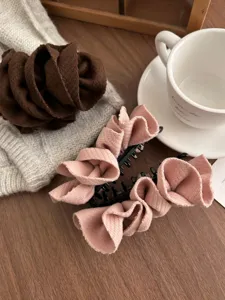 Detailed view of pink fabric flower banana hair clip on wooden surface
