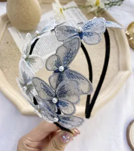 Vista detallada de la diadema de mariposa bordada con elegantes detalles de perlas blancas