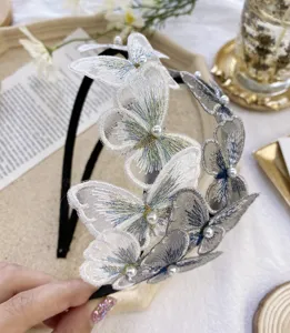 Primer plano detallado de diadema con mariposas bordadas blancas y cuentas de perlas