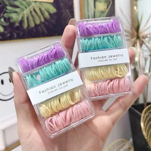 Close-up of pastel-colored elastic hair bands set in transparent cases held by hands