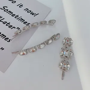Close-up of silver hair clips with sparkling crystal rhinestones on a white surface