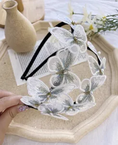 Vista detallada de aplicaciones de mariposas blancas bordadas con adornos de perlas y strass