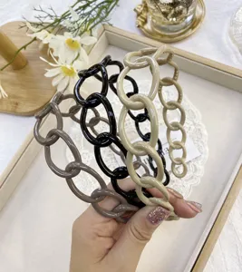 Detailed close-up of glossy chain-link headbands in chic black, beige, and taupe colors.