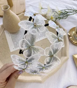 Primer plano de la diadema de mariposas bordadas en blanco con perlas y pedrería