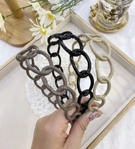 Close-up detail of three minimalist plastic chain-link headbands in neutral colors