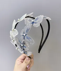 Detalle de cerca de una diadema de mariposa bordada blanca con delicados toques de perla