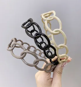 Close-up of minimalist plastic chain-link headbands in three glossy neutral colors