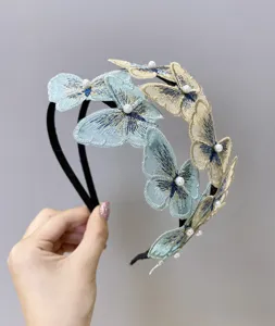 Primer plano que muestra el intrincado bordado de alas de mariposa y perlas en una diadema