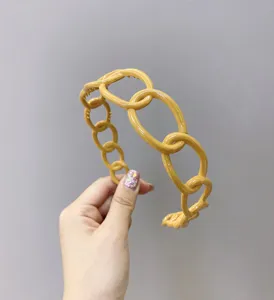 Detailed macro view of mustard yellow chain-link plastic headband with a high-gloss finish