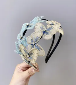Detalle de parches de mariposa bordados y pedrería en una diadema fina y elegante
