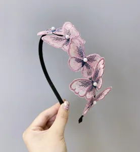 Detalle de cerca de mariposas bordadas rosas y perlas en una diadema fina negra