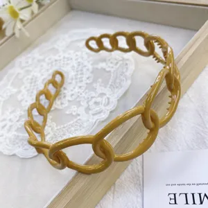 Close-up macro view of minimalist yellow chain-link plastic headband with glossy finish