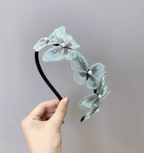 Primer plano de una elegante diadema de mariposa bordada en azul claro con perlas.