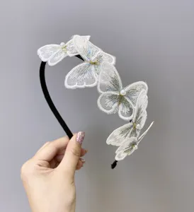 Vista detallada de una elegante diadema de mariposa bordada blanca con perlas finas