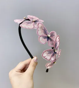 Vista detallada de la diadema de mariposas bordadas rosas con detalles de pedrería