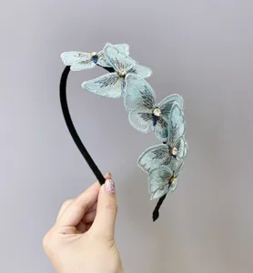 Primer plano de una diadema de mariposas bordadas azul claro con brillantes