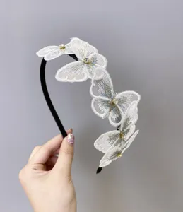 Primer plano de diadema de mariposa bordada blanca con brillantes centros de diamantes