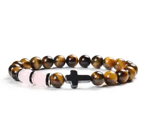 Detailed close-up of yellow tiger eye stone and pink chalcedony beaded bracelet with black cross.