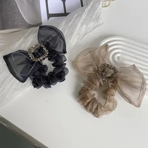 Detailed view of elegant mesh bow scrunchies with sparkling rhinestone buckles in two colors