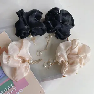 Detailweergave van oversized organza scrunchies met parel- en strasskwastjes