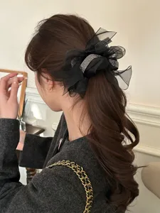Detail van een elegante zwarte strik haarelastiek met glanzende strass band