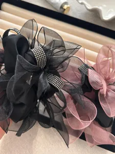 Gedetailleerd overzicht van elegante zwarte en roze strikscrunchies met glimmende strass