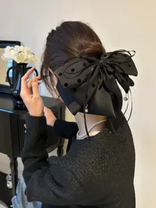 Vue détaillée d'une grande pince à cheveux nœud à pois noirs sur un chignon bas élégant