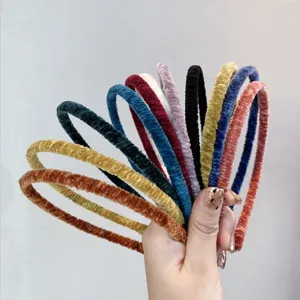 Close-up of colorful velvet pleated headbands held in hand, showing soft texture details