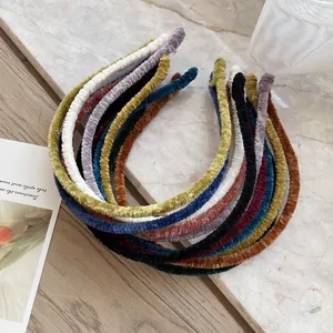 Detailed view of multiple colorful winter velvet pleated thin headbands on marble